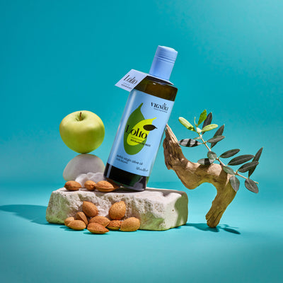 Vignoli Nocellara del Belice Monocultivar Extra Virgin Olive Oil front of 16.9oz bottle on stone with apple, olive branch and nuts