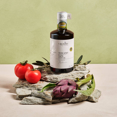 Vignoli Extra Virgin Olive Oil IGP Toscana - Medium front of 16.9oz bottle on rocks with tomato and artichoke