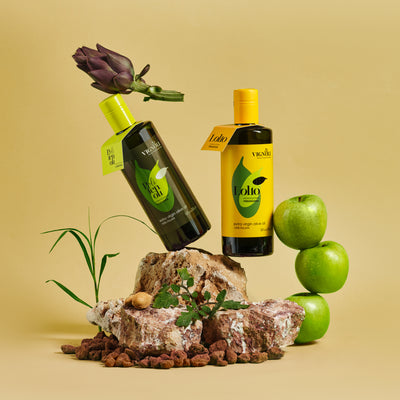 Vignoli Puglia Lollo Monocultivar EVOO's Duo 16.9oz bottles on rock with apples and artichoke