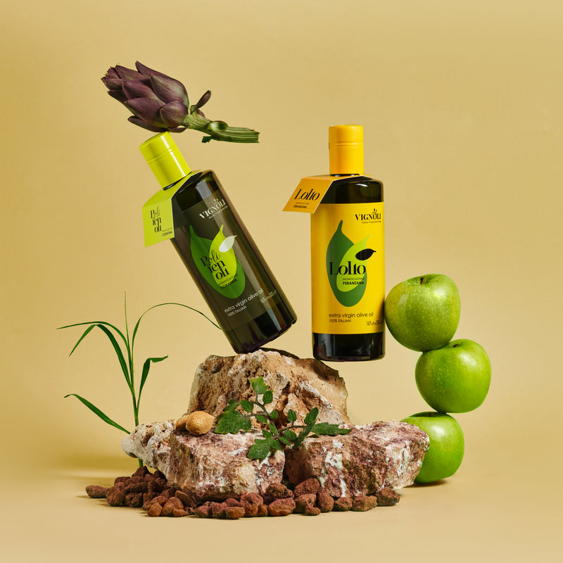 Vignoli Peranzana Monocultivar Extra Virgin Olive Oil front of 16.9oz bottle on stone with pairing bottle and apples and artichoke