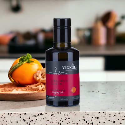 Blood Orange Infused Extra Virgin Olive Oil front of 8.5oz bottle on kitchen table with tomato in background