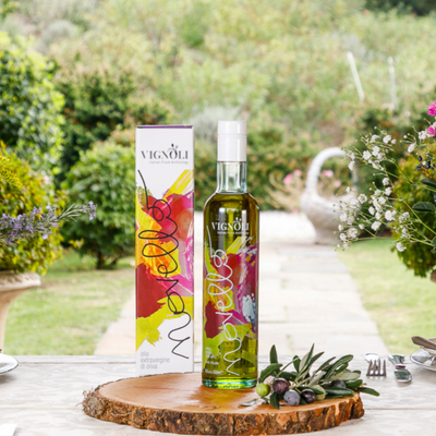 Vignoli Novello Extra Virgin Olive Oil front of 16.9oz bottle with packaging box beside and garden in background