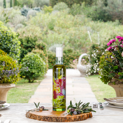 Vignoli Novello Extra Virgin Olive Oil front of 16.9oz bottle on table with garden in background