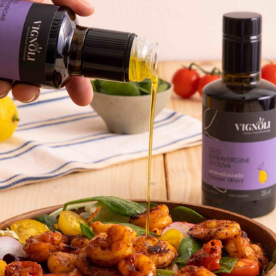 Vignoli Meyer Lemon Infused Extra Virgin Olive Oil front of 8.5oz bottle pouring over shrimp salad