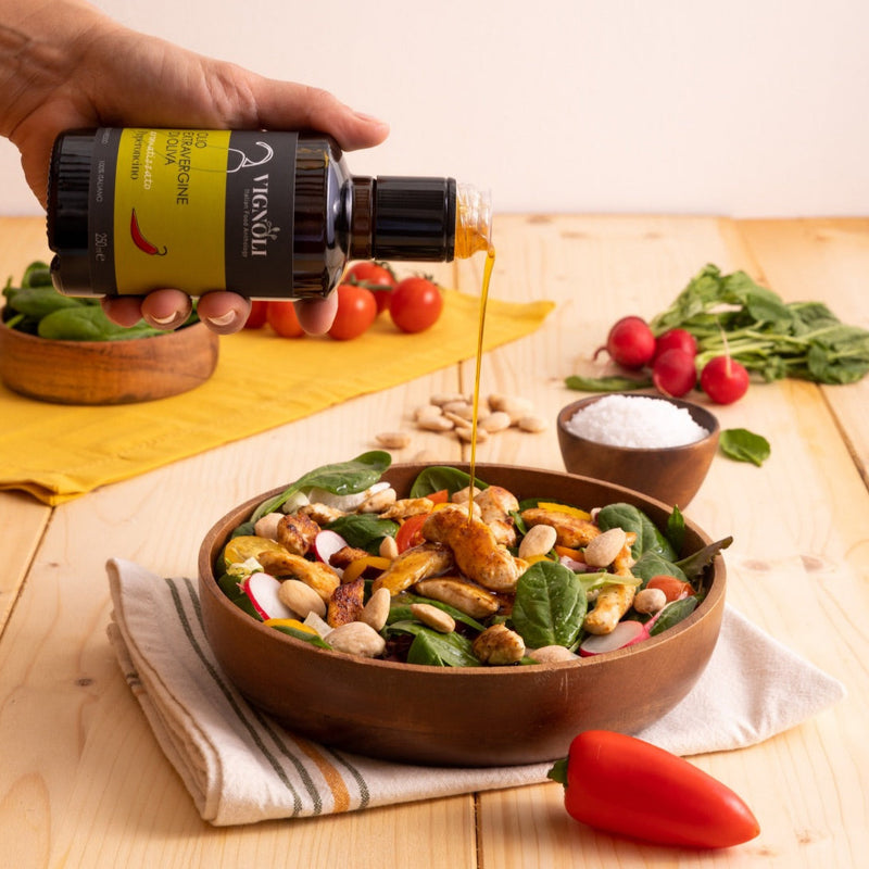 Chili Pepper Infused Extra Virgin Olive Oil front of 8.5oz bottle pouring over chicken salad