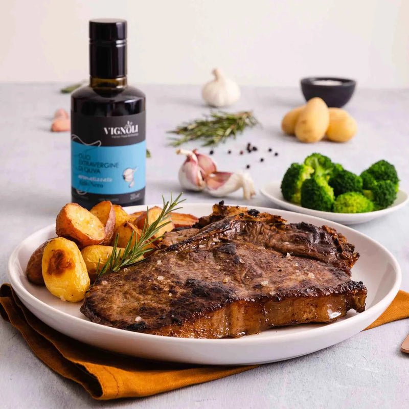 Black Garlic Infused Extra Virgin Olive Oil front of 8.5oz bottle with steak, potatoes and broccoli
